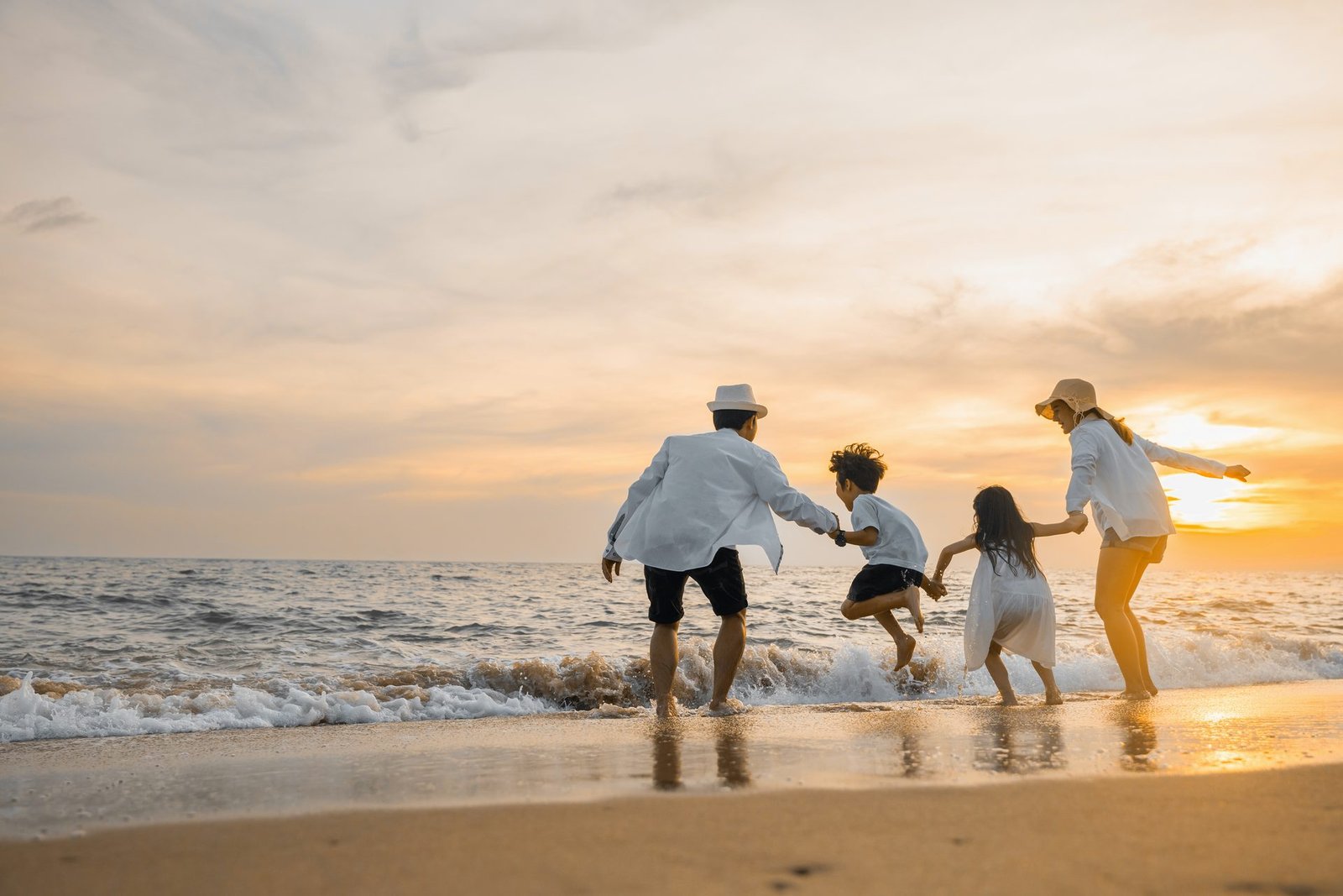 Family running into the sea at sunset on the Costa del Sol