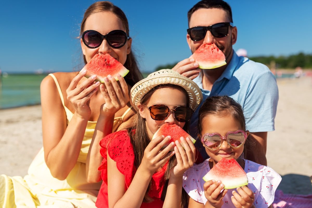Family enjoying watermelon on the beach after relocating to the Costa del Sol
