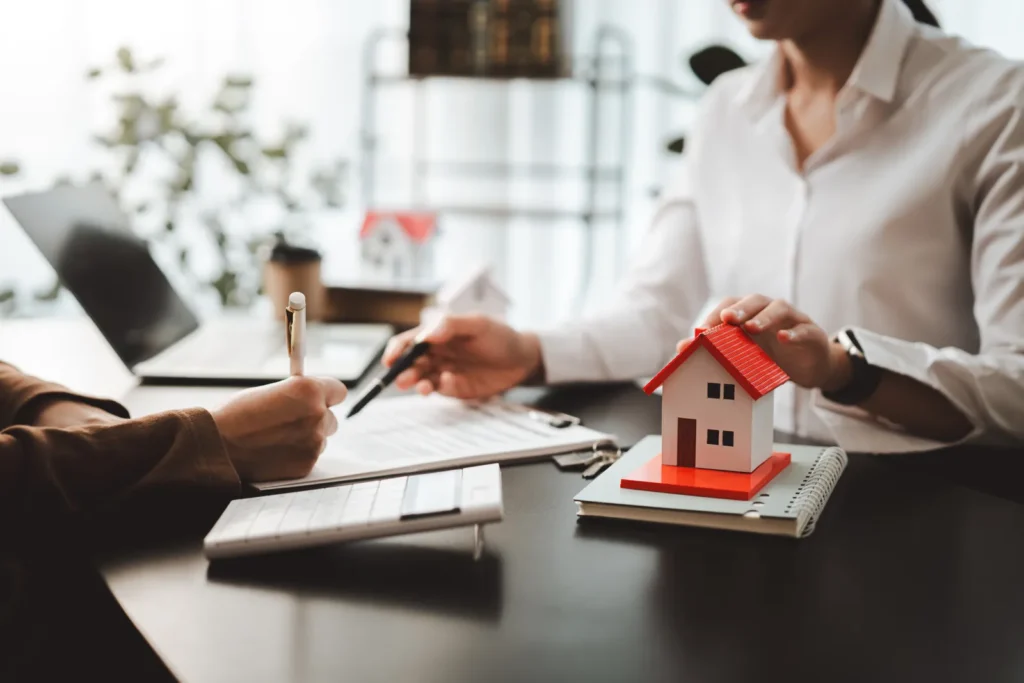 Signing a Spanish mortgage offer with a house model and calculator on the desk